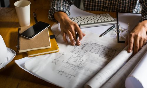 Creative architect projecting on the big drawings in the dark loft office or cafe with dark and retro style.